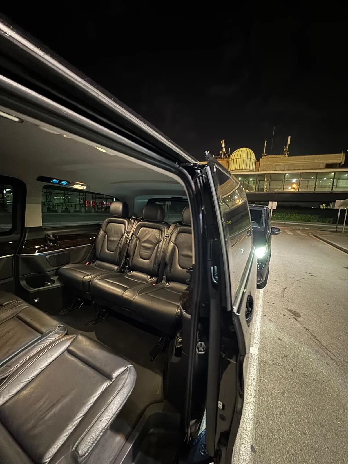 Row of three leather seats in the Mercedes V-Class seen through the open sliding door
